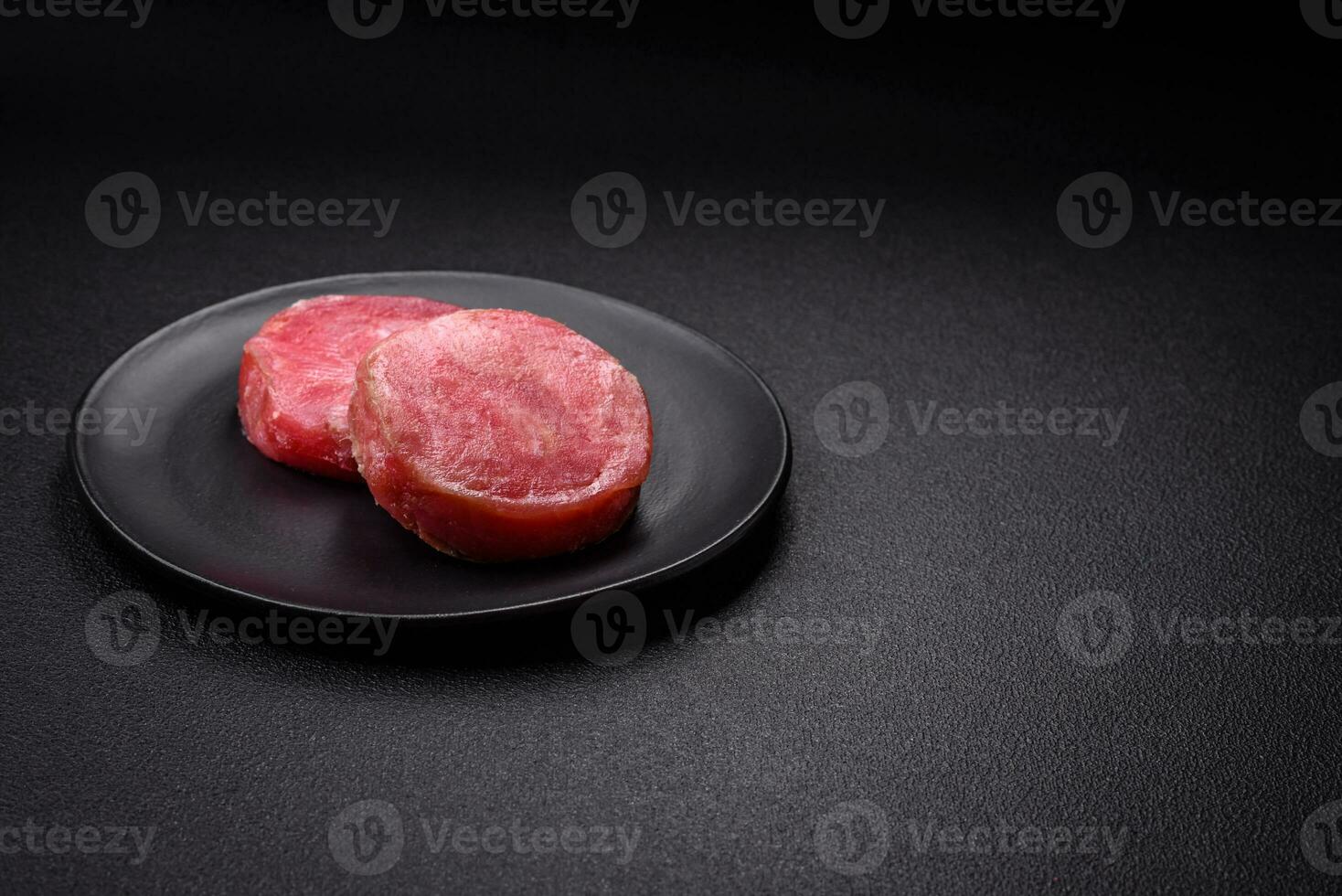 Round shape steaks of raw juicy tuna with salt and spices photo