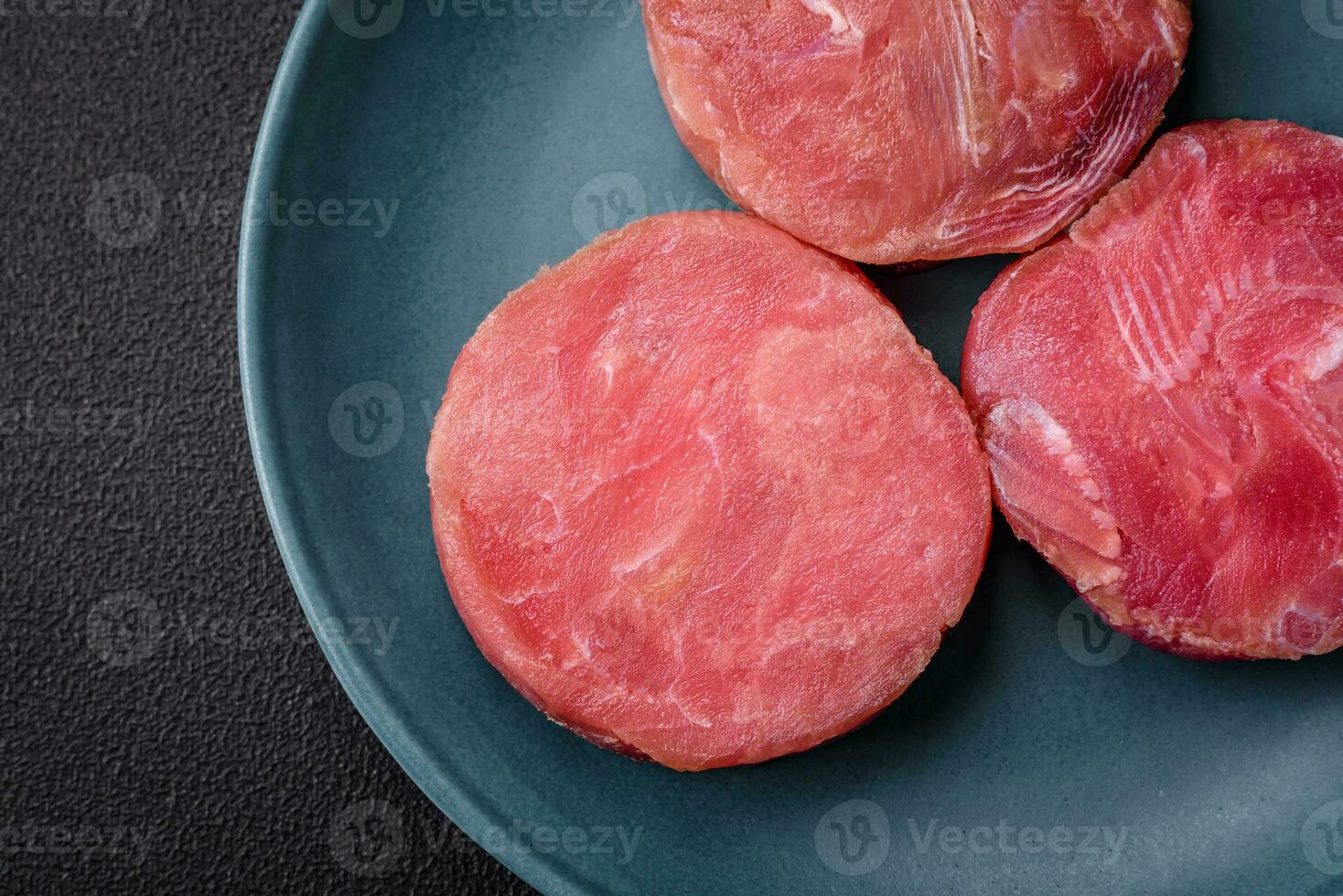 Round shape steaks of raw juicy tuna with salt and spices photo