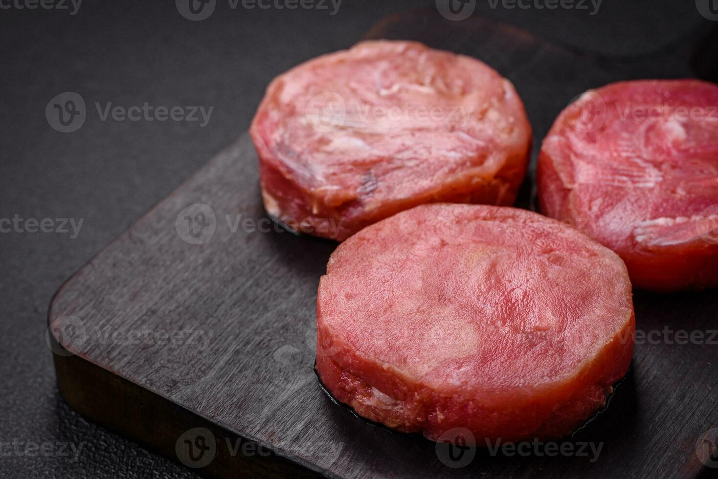 Round shape steaks of raw juicy tuna with salt and spices photo