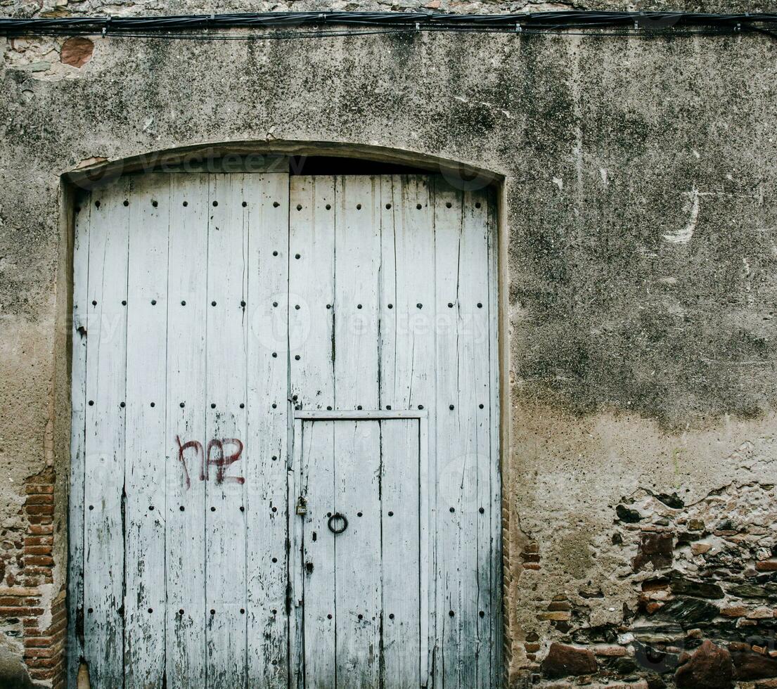 Old closed fabric door with iron fittings. Medieval wooden door in a stone wall. T photo