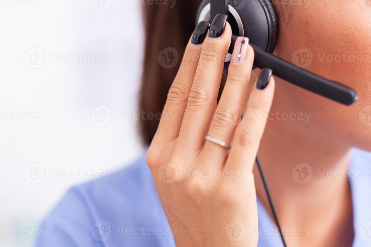 Medical secretary having a conversation with patients while wearing headphones with microphone. Female nurse, doctor during call examination with sick person during consultation, medicine. photo