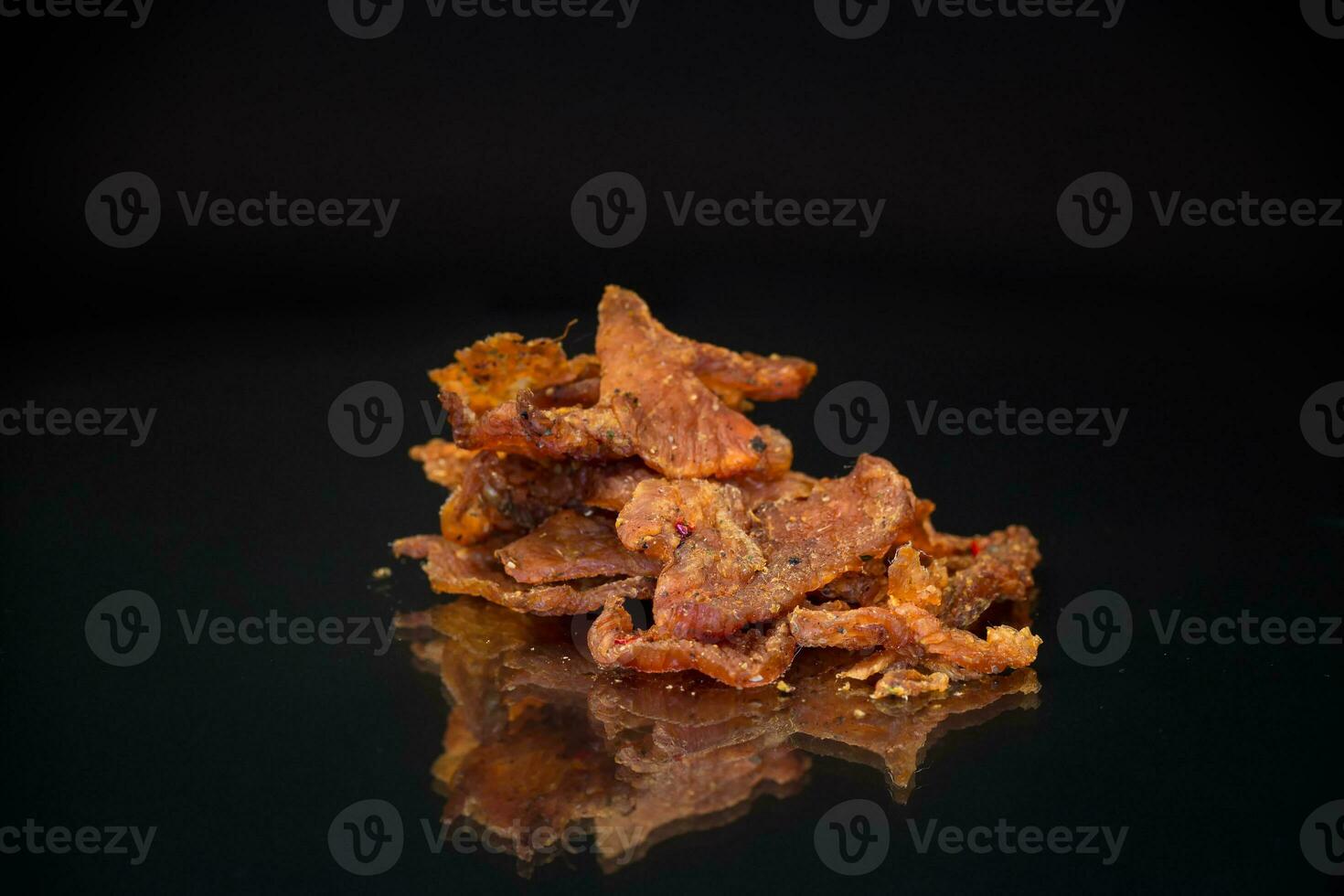 handful of dried meat marinated with spices, isolated on a black background. photo