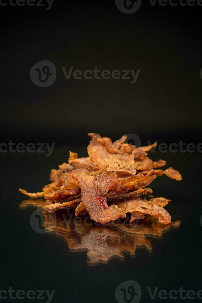 handful of dried meat marinated with spices, isolated on a black background. photo