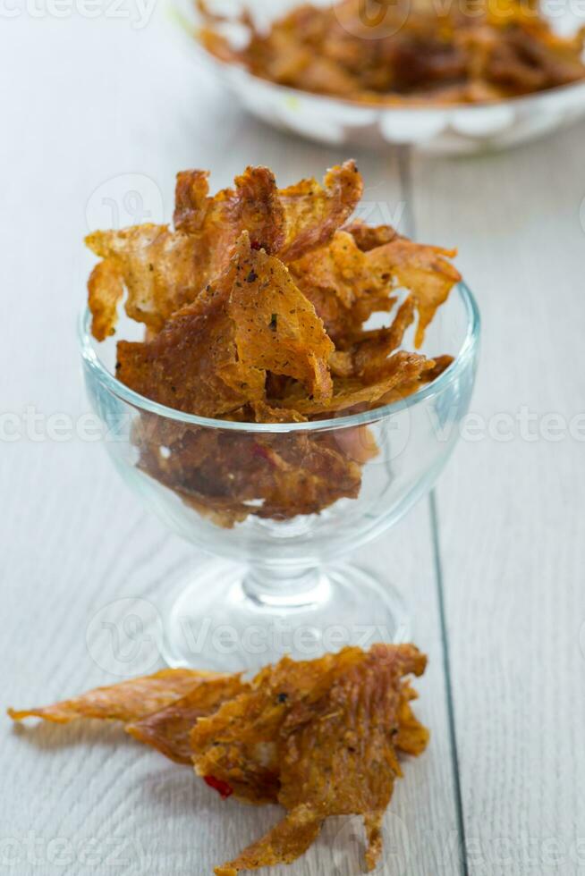 dried meat with spices in a glass bowl, light wooden background. photo