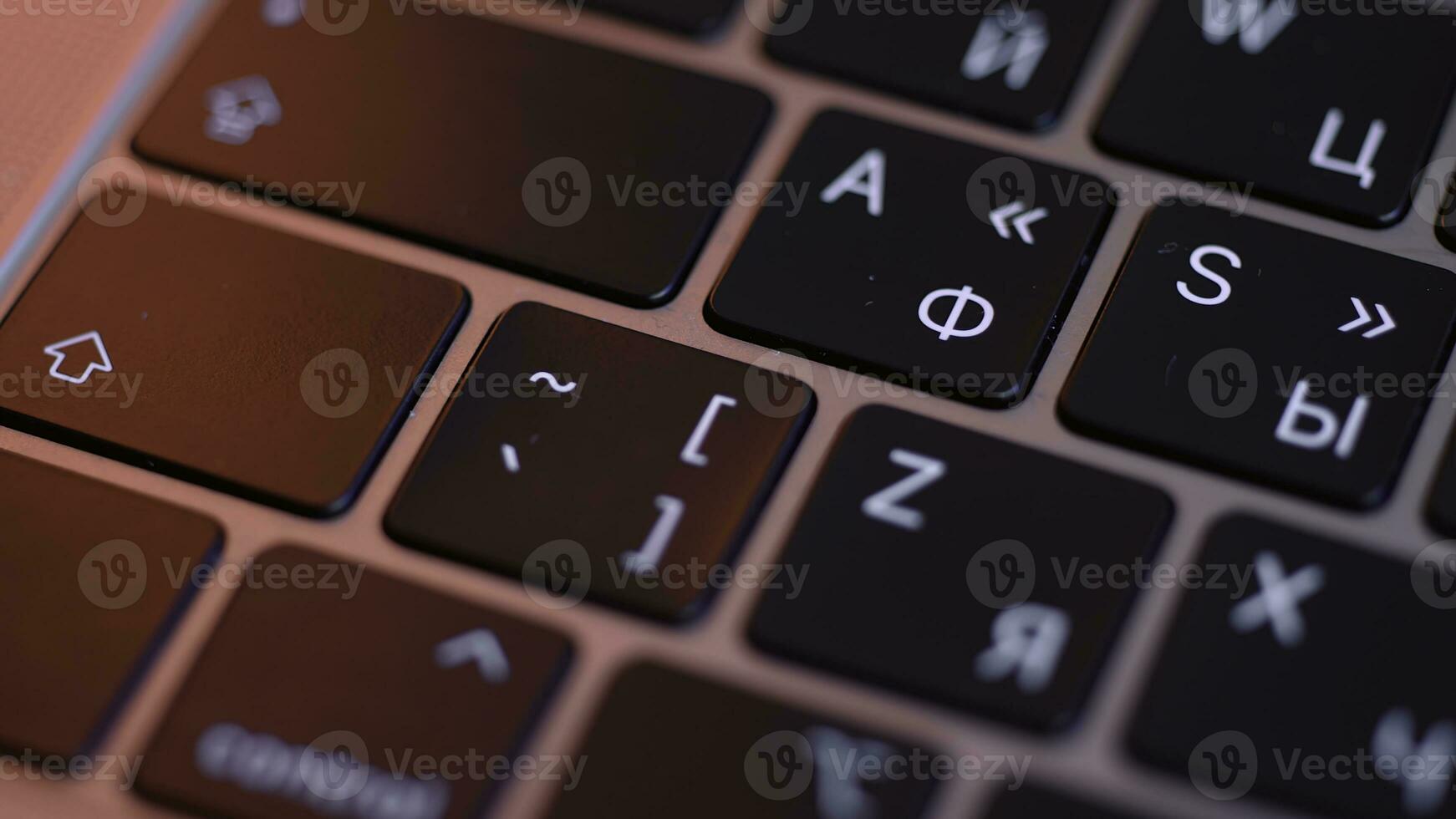 Close up of buttons on computer keyboard, macro background. Action. Black modern laptop buttons under the red lamp light, concept of technologies and devices. photo