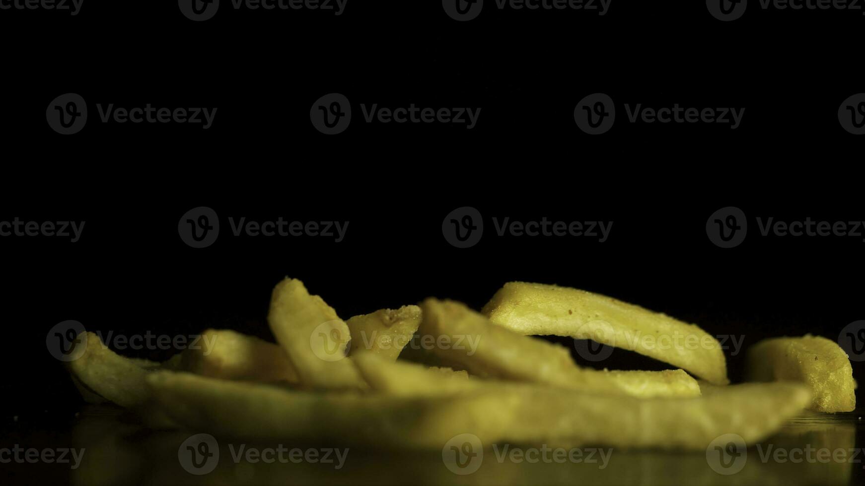 Fries falling isolated on black background. French fries fall on the table isolated on black background. Flying chips closeup. photo