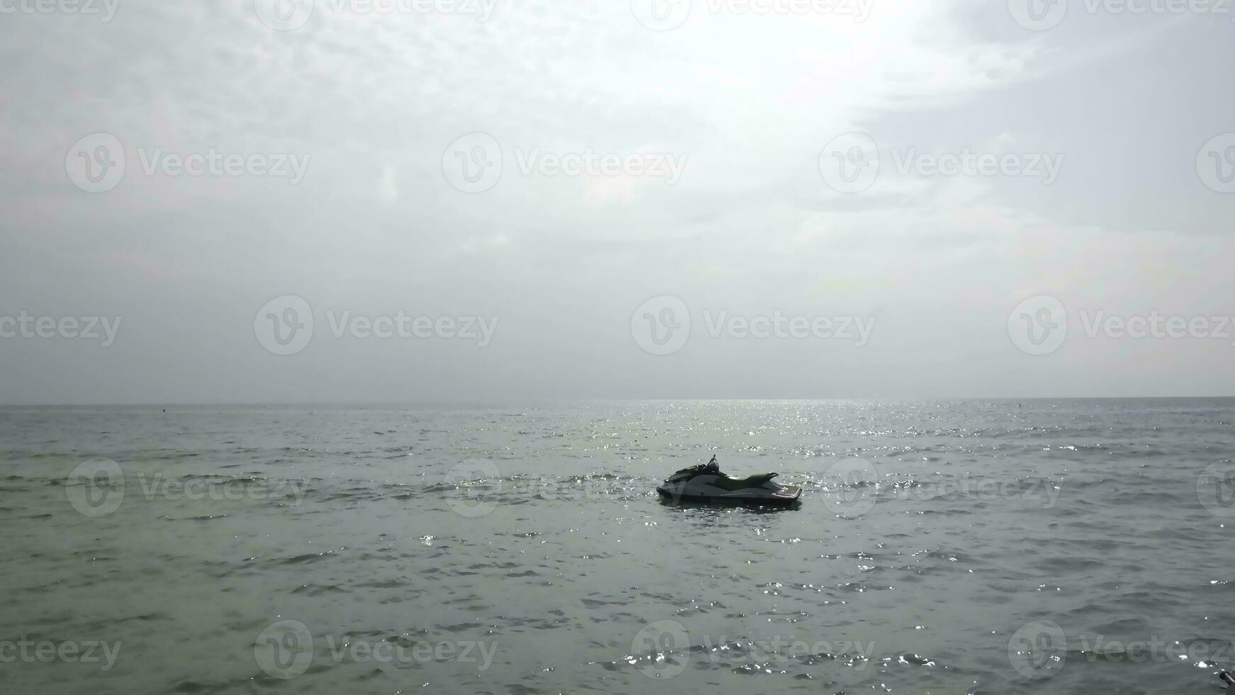 Watercraft or jet ski on the water in the sea and sunset background. Jet Ski Moored in the sea ot amazing blue background, Beautiful landscape with jet ski or water bike at the sea with waves and sun photo