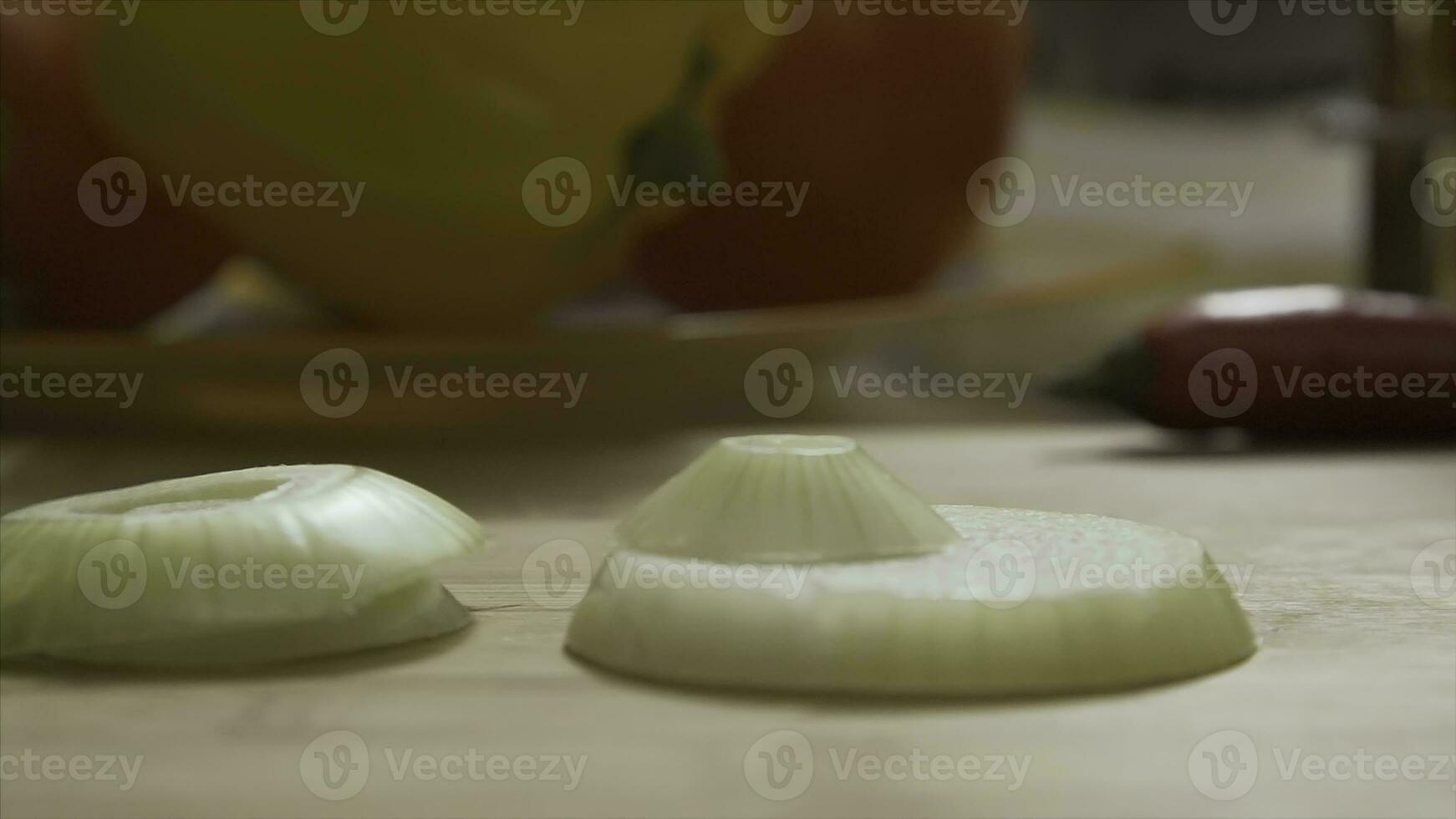 Falling sliced ring onions on wooden cutting board. Closeup of falling circles of green onion on glass bowl from cutting board, slow motion. Sliced leek falling on wooden desk for slicing food photo