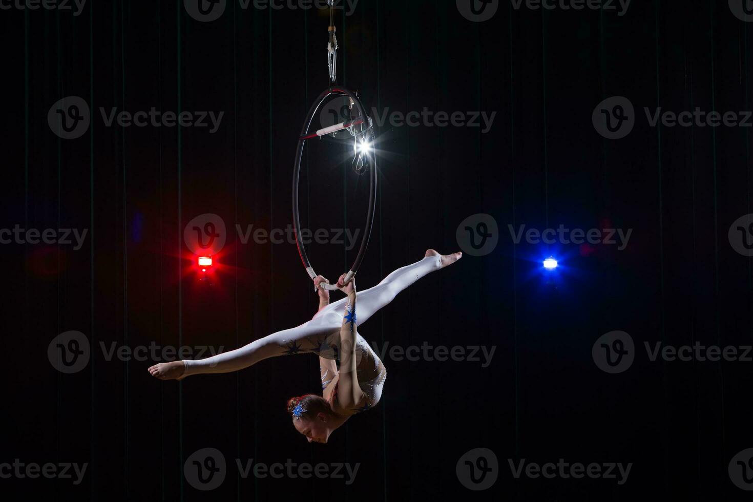 Performs a circus girl actress. Circus aerial gymnast on the hoop. Acrobatics. Teenager performs an acrobatic trick in the air photo