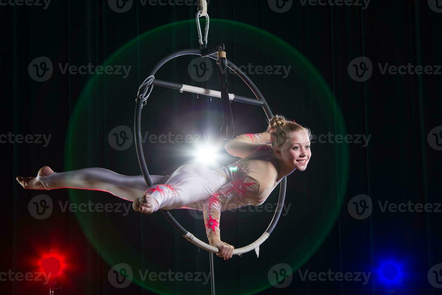 Performs a circus girl actress. Circus aerial gymnast on the hoop. Acrobatics. Teenager performs an acrobatic trick in the air photo