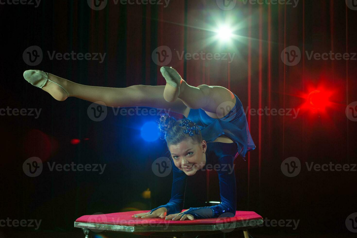 un niña con un flexible cuerpo. realiza un circo artista. circo gimnasta. equilibrio acto. el niño realiza un acrobático truco foto