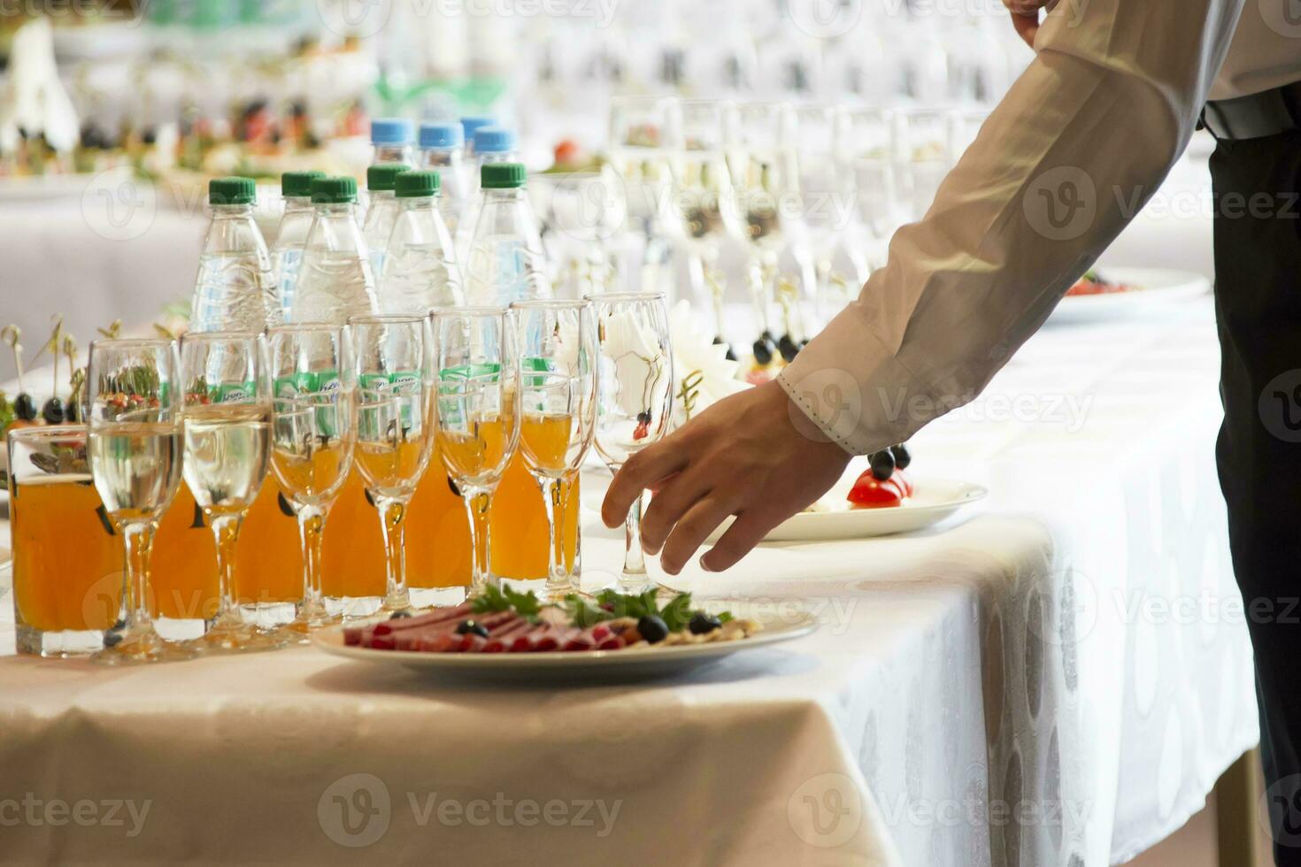 Waiter's hands pouring a drink into glasses photo