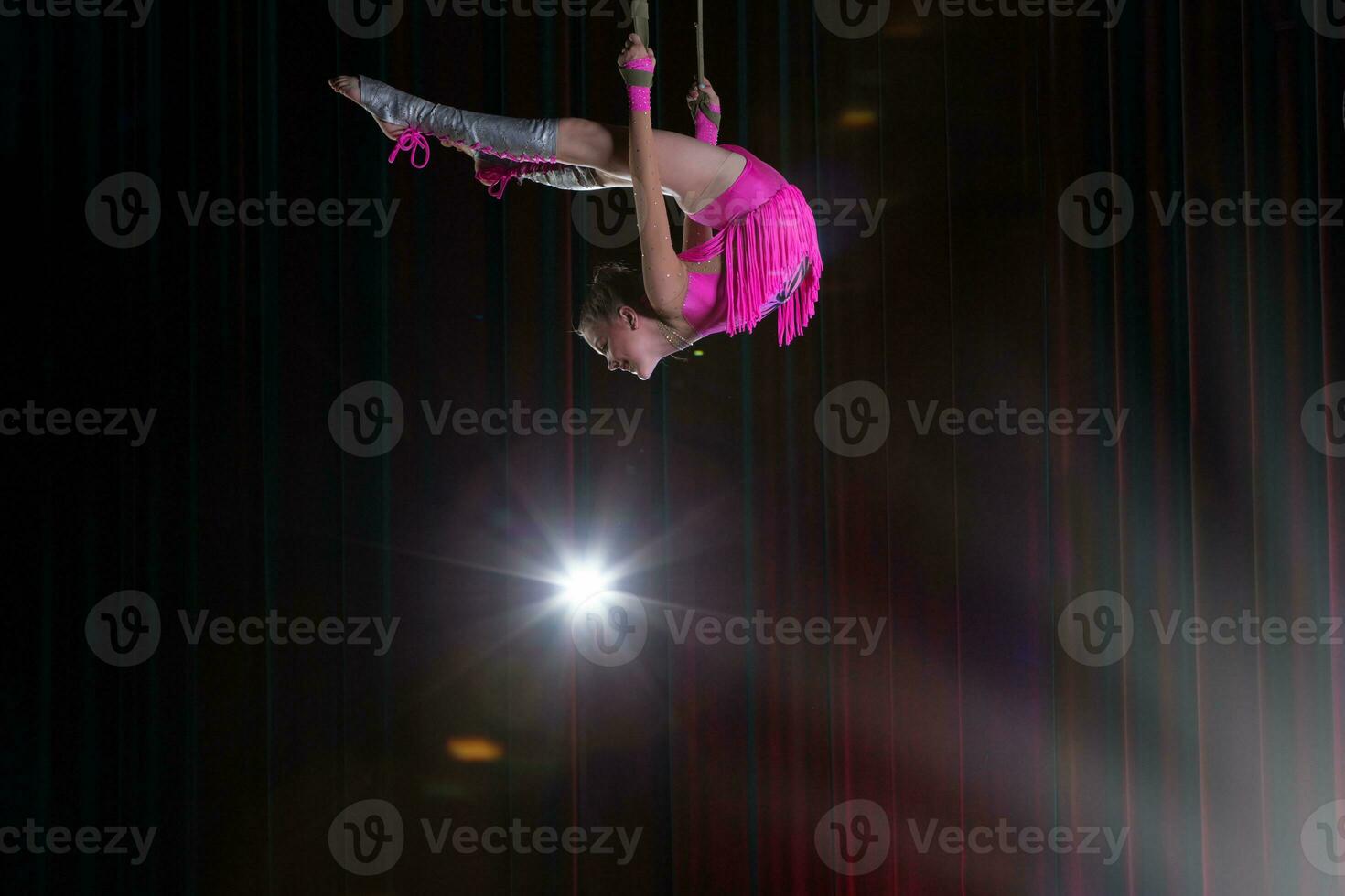 Circus artist acrobat performance. The girl performs acrobatic elements in the air. Circus gymnast on the stage photo