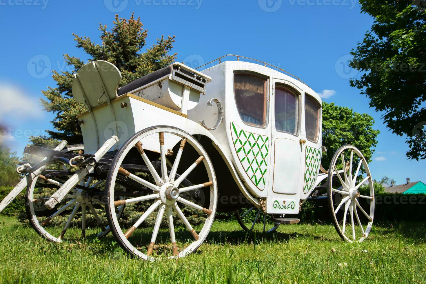 An antique white carriage from the nineteenth century on a green lawn. The prototype of a modern car. photo
