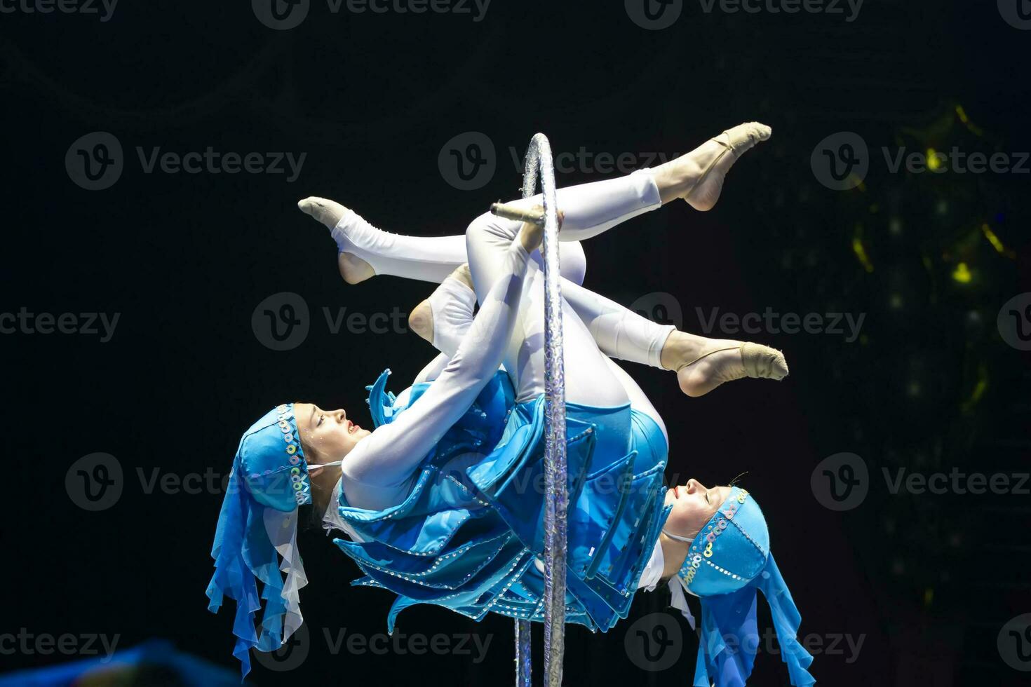 Two acrobat girls show a circus number on a dark background. Acrobatic performance. photo