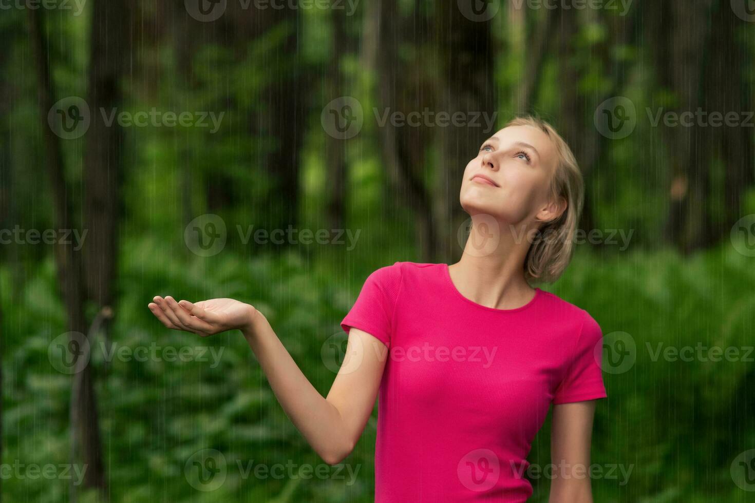 beautiful girl rejoices in the rain while walking in the forest photo