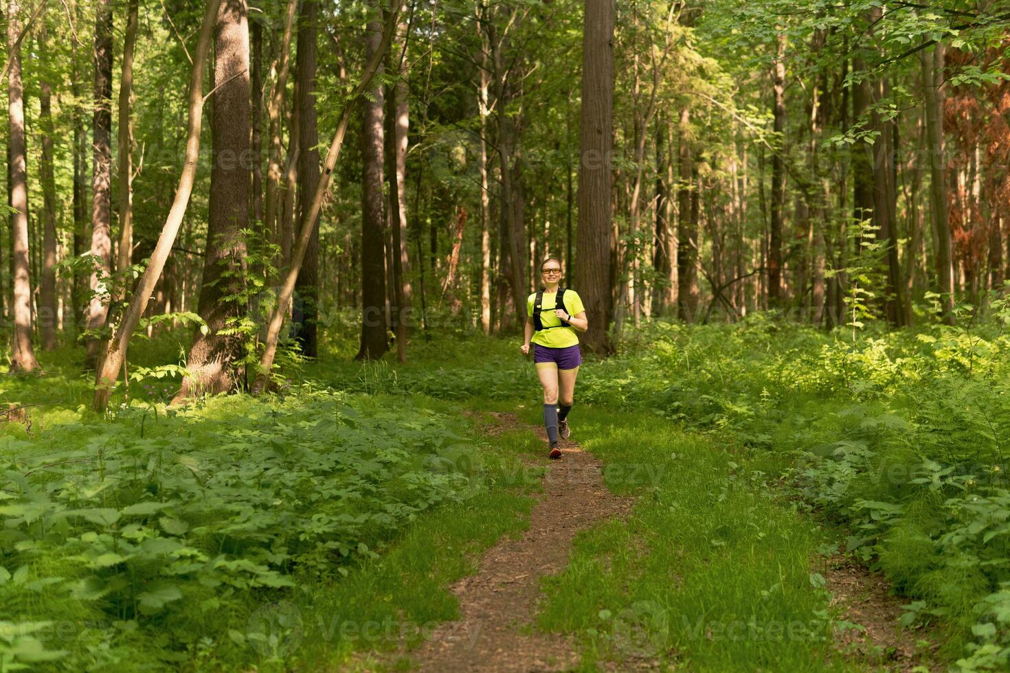 joven mujer trotar en un camino en un natural bosque parque foto