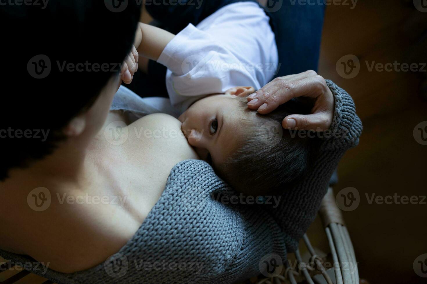 young woman breastfeeding her little son while sitting in a cozy armchair photo