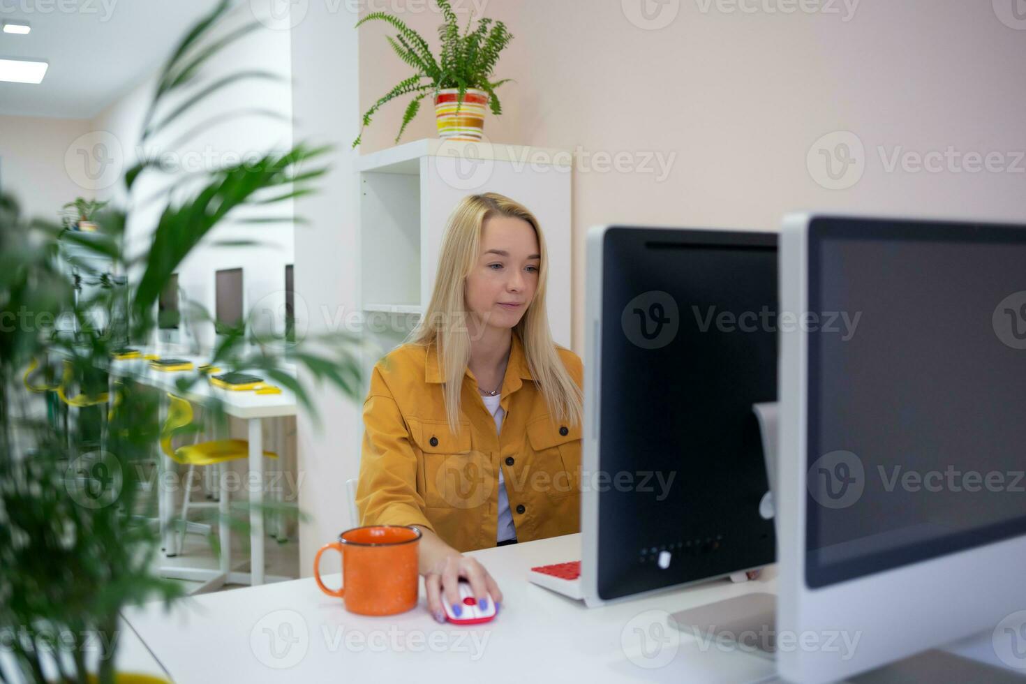 young woman sits at a computer in the office. remote work concept photo