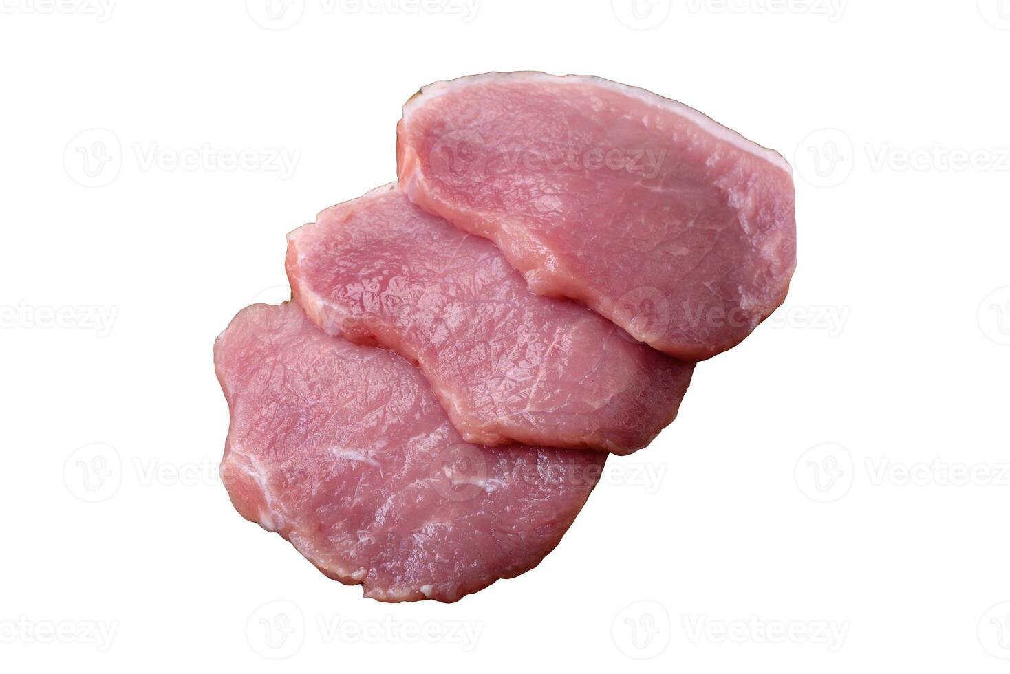A piece of raw fresh pork on a wooden cutting board with spices and herbs photo