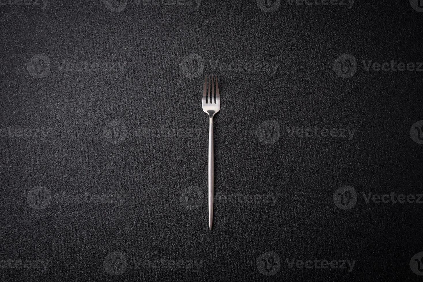 Kitchen fork made of steel on a dark textured background photo