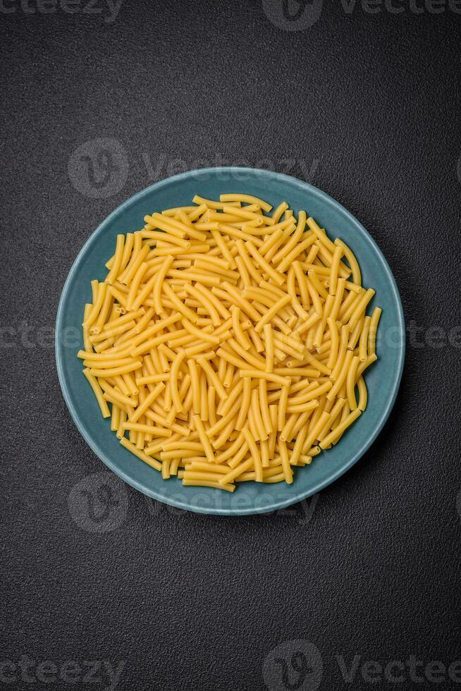 Raw whole grain wheat pasta with salt and spices in a ceramic plate photo