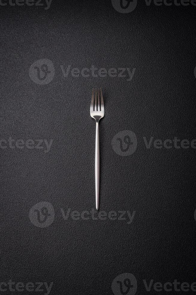 Kitchen fork made of steel on a dark textured background photo
