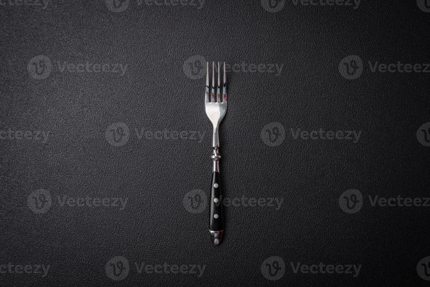 Kitchen fork made of steel on a dark textured background photo