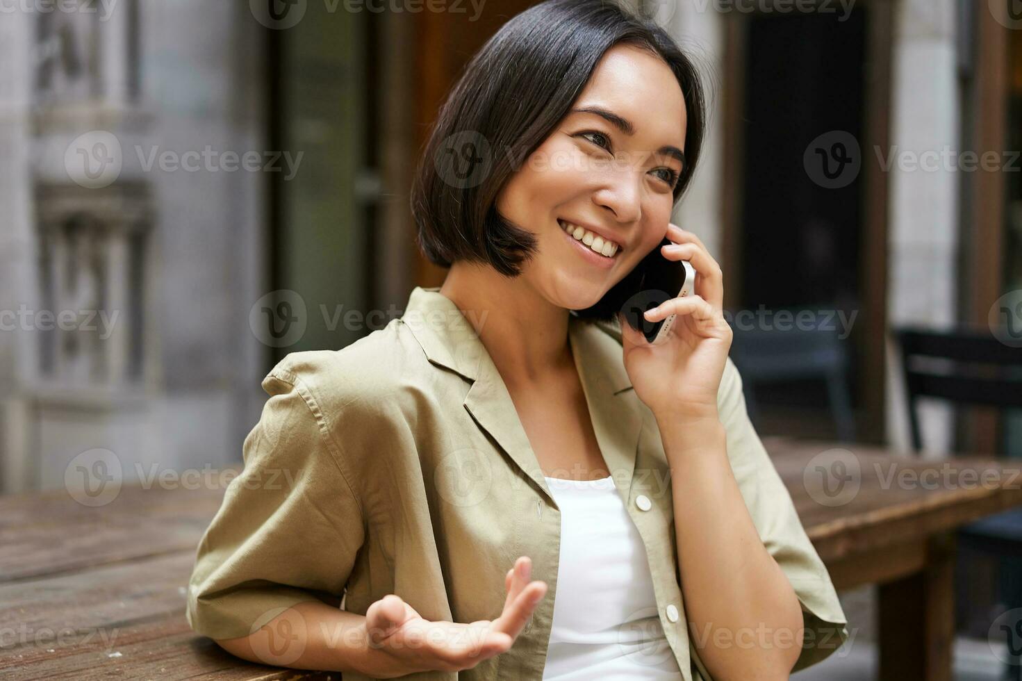 Young woman having conversation on mobile phone, sitting outdoors and making phone call, using smartphone, talking photo
