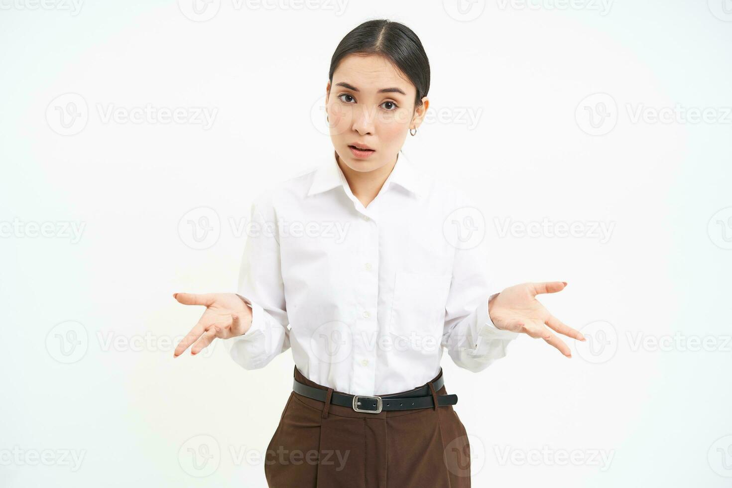Image of confused asian saleswoman, spreads hands sideways with clueless face expression, shrugs shoulders, white background photo