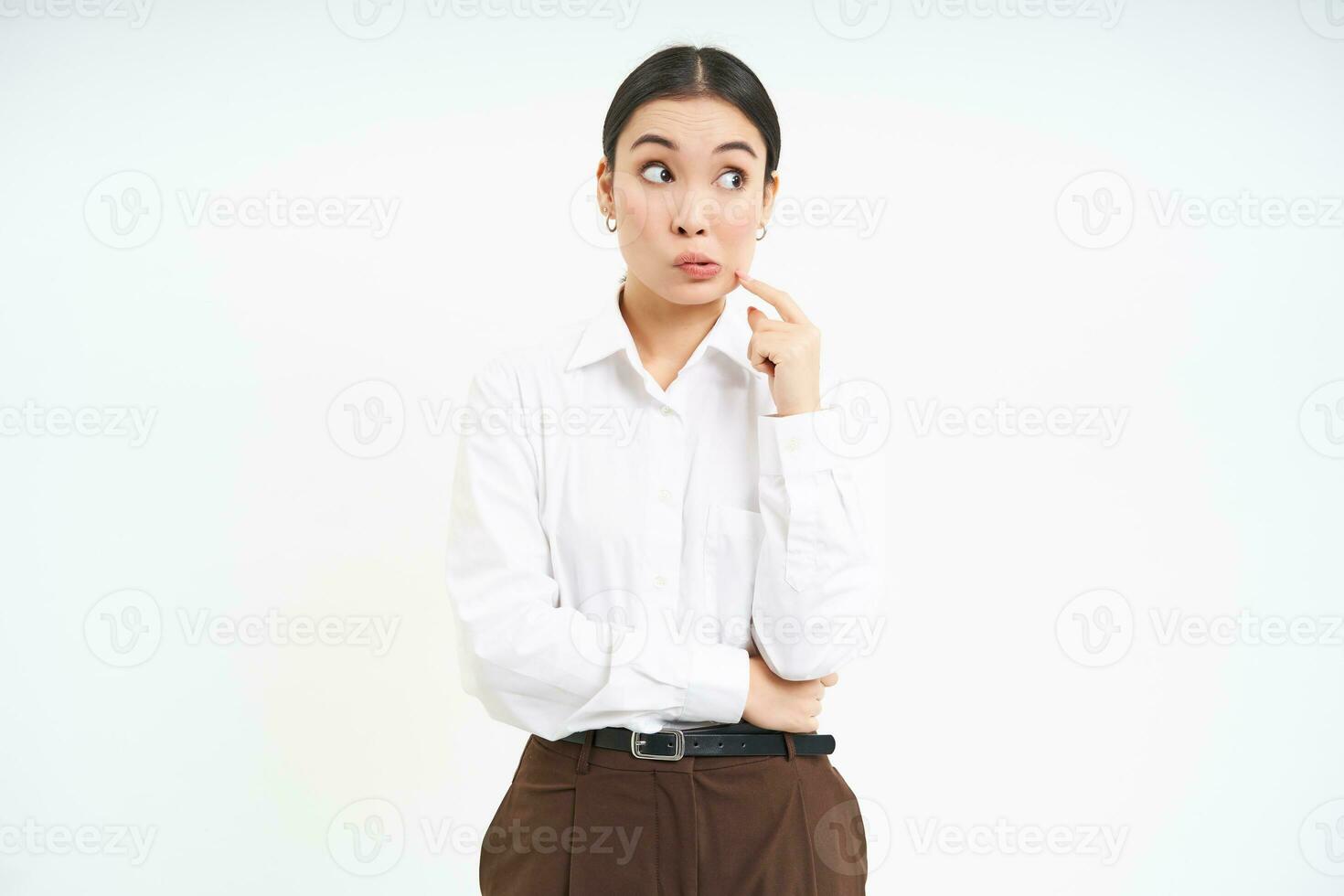 Thoughtful asian woman, businesswoman scratches her face and thinks, makes decision, white background photo