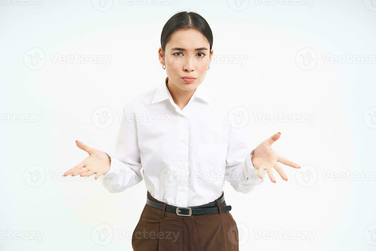 Image of confused asian saleswoman, spreads hands sideways with clueless face expression, shrugs shoulders, white background photo