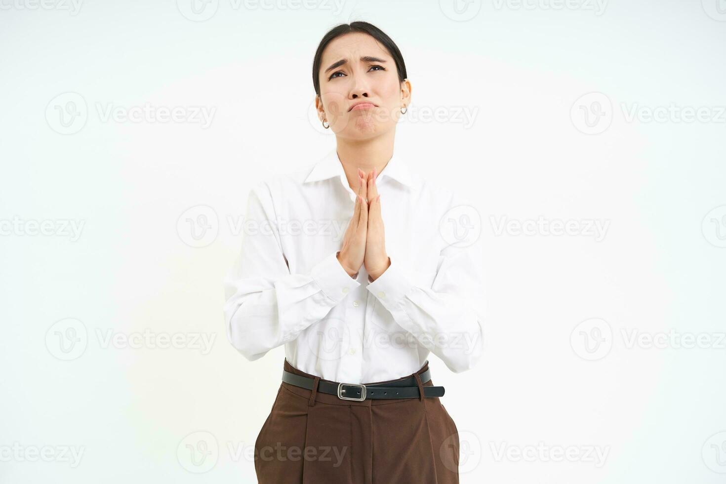 Sad asian woman pleading, looks up at Lord with hands in pray, begging for help, white background photo