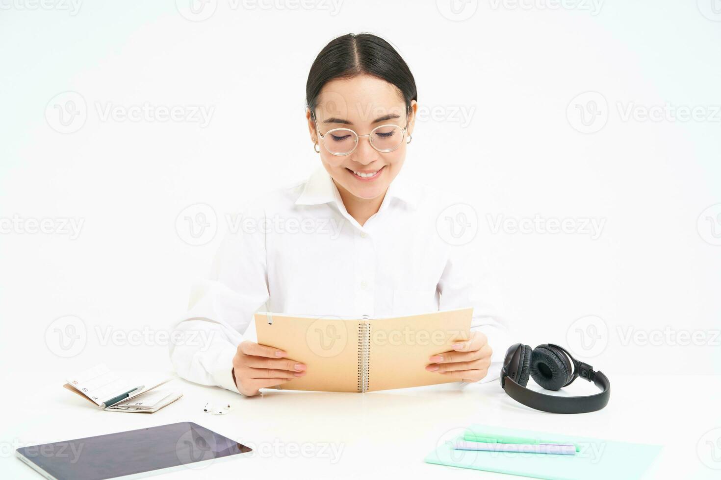 Image of hardworking student, asian woman in glasses studying, holding notebook, working on project, isolated over white background photo