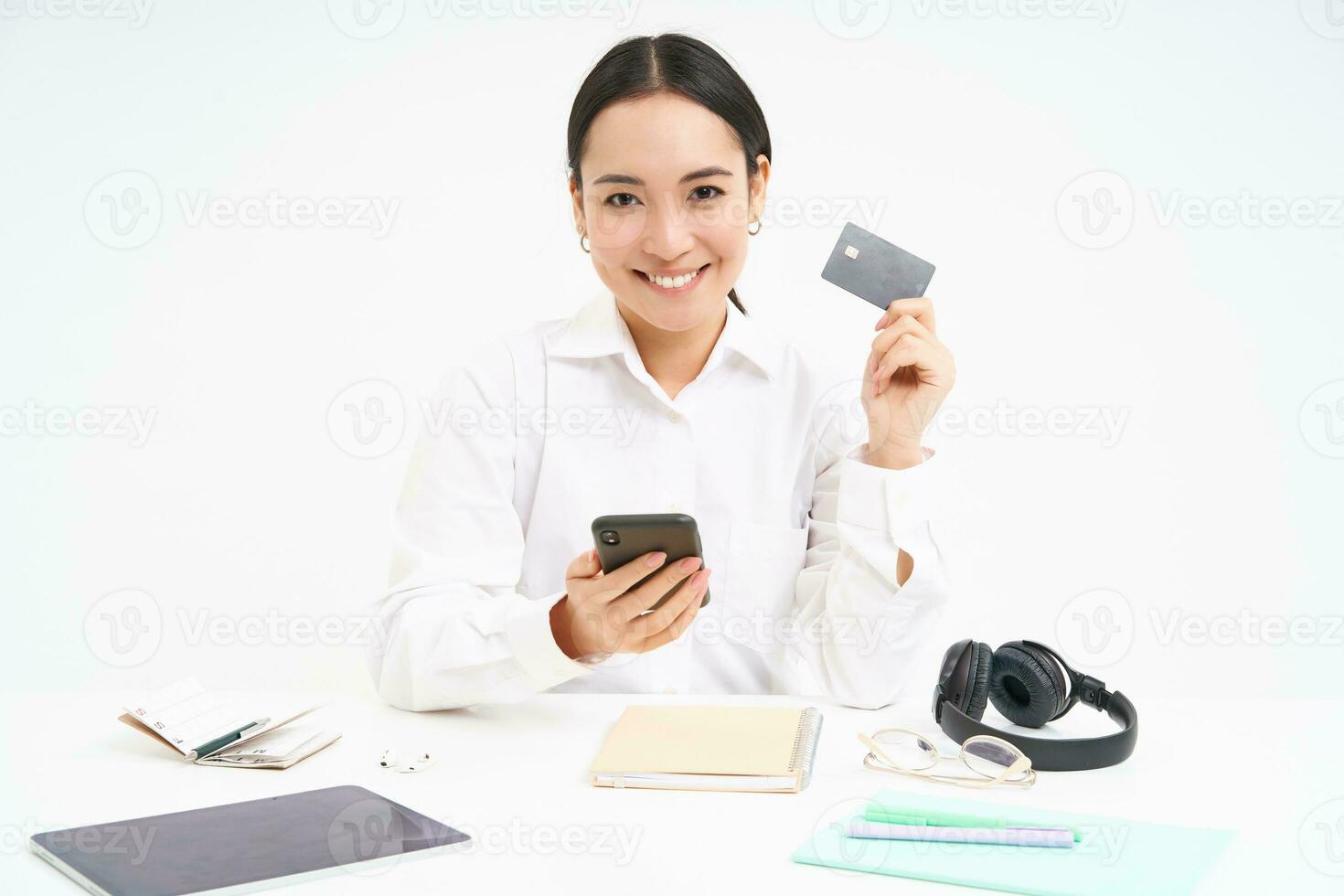 Corporate and business. Asian woman in office, holds smartphone and credit card, paying online, setting up direct debit online, white background photo