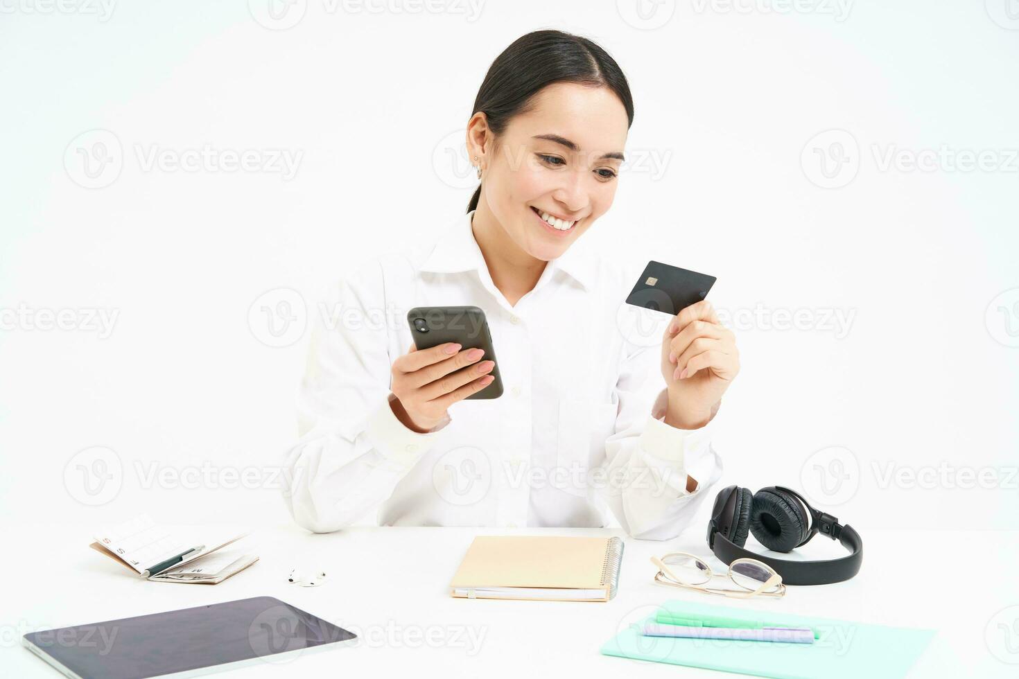 Corporate and business. Asian woman in office, holds smartphone and credit card, paying online, setting up direct debit online, white background photo