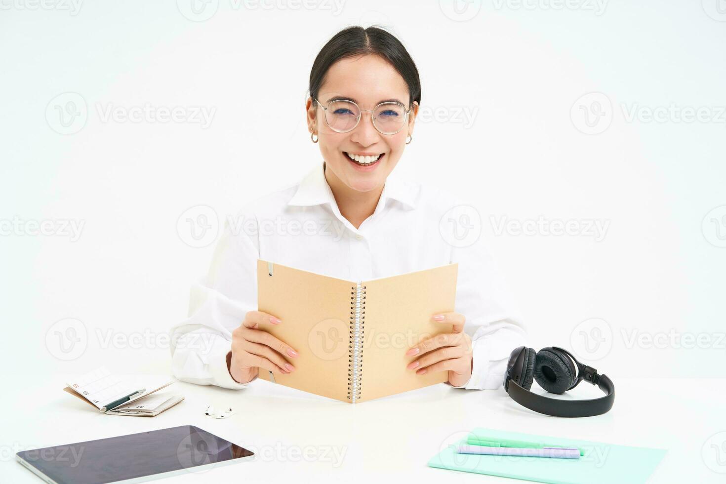 Image of hardworking student, asian woman in glasses studying, holding notebook, working on project, isolated over white background photo