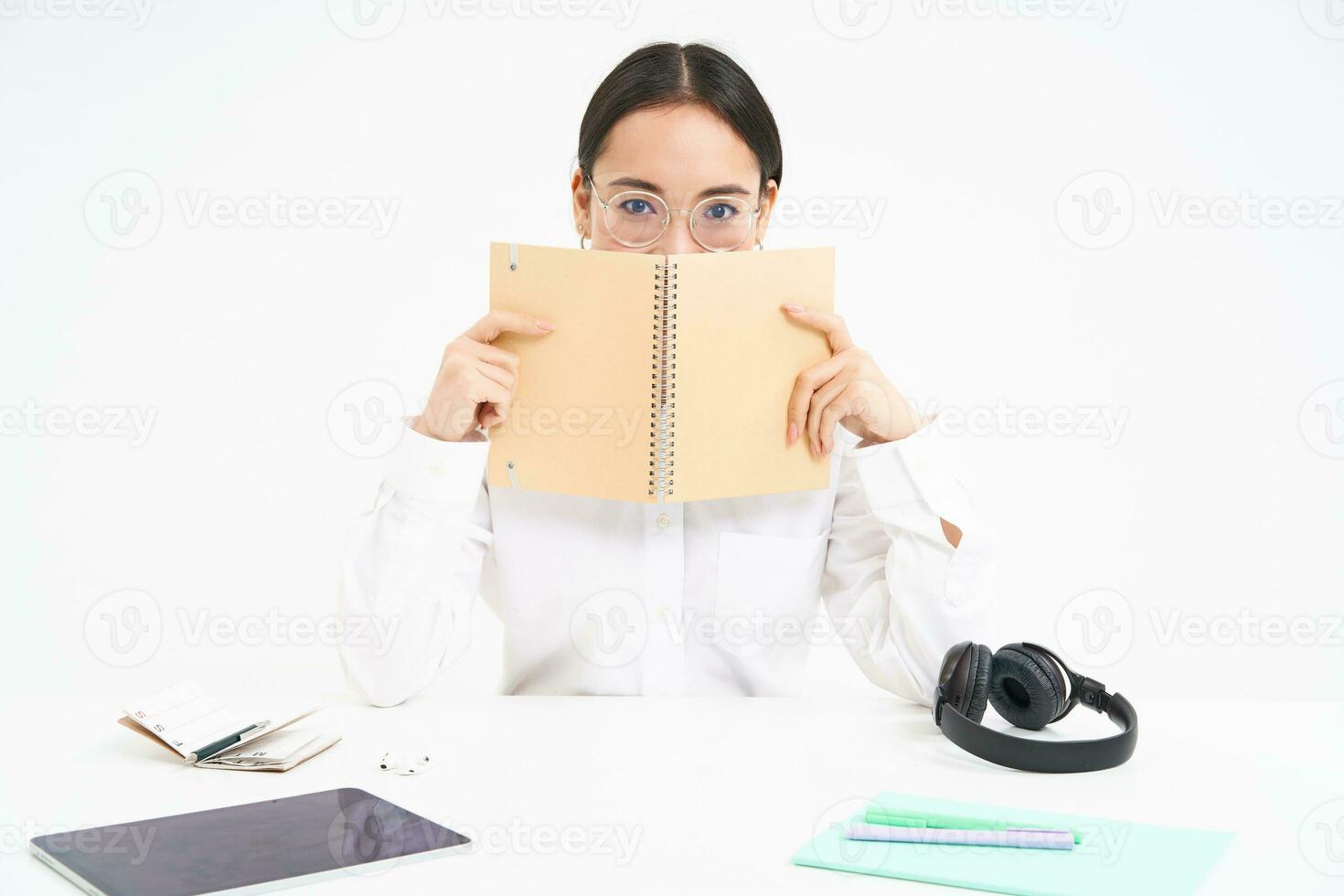 Image of hardworking student, asian woman in glasses studying, holding notebook, working on project, isolated over white background photo