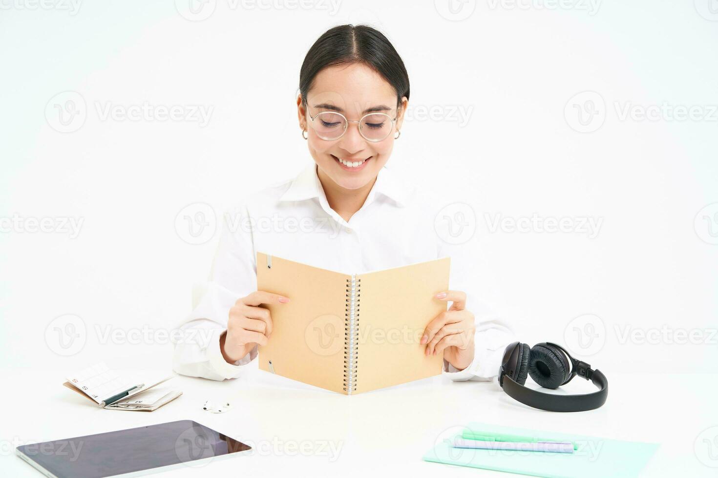 Image of hardworking student, asian woman in glasses studying, holding notebook, working on project, isolated over white background photo