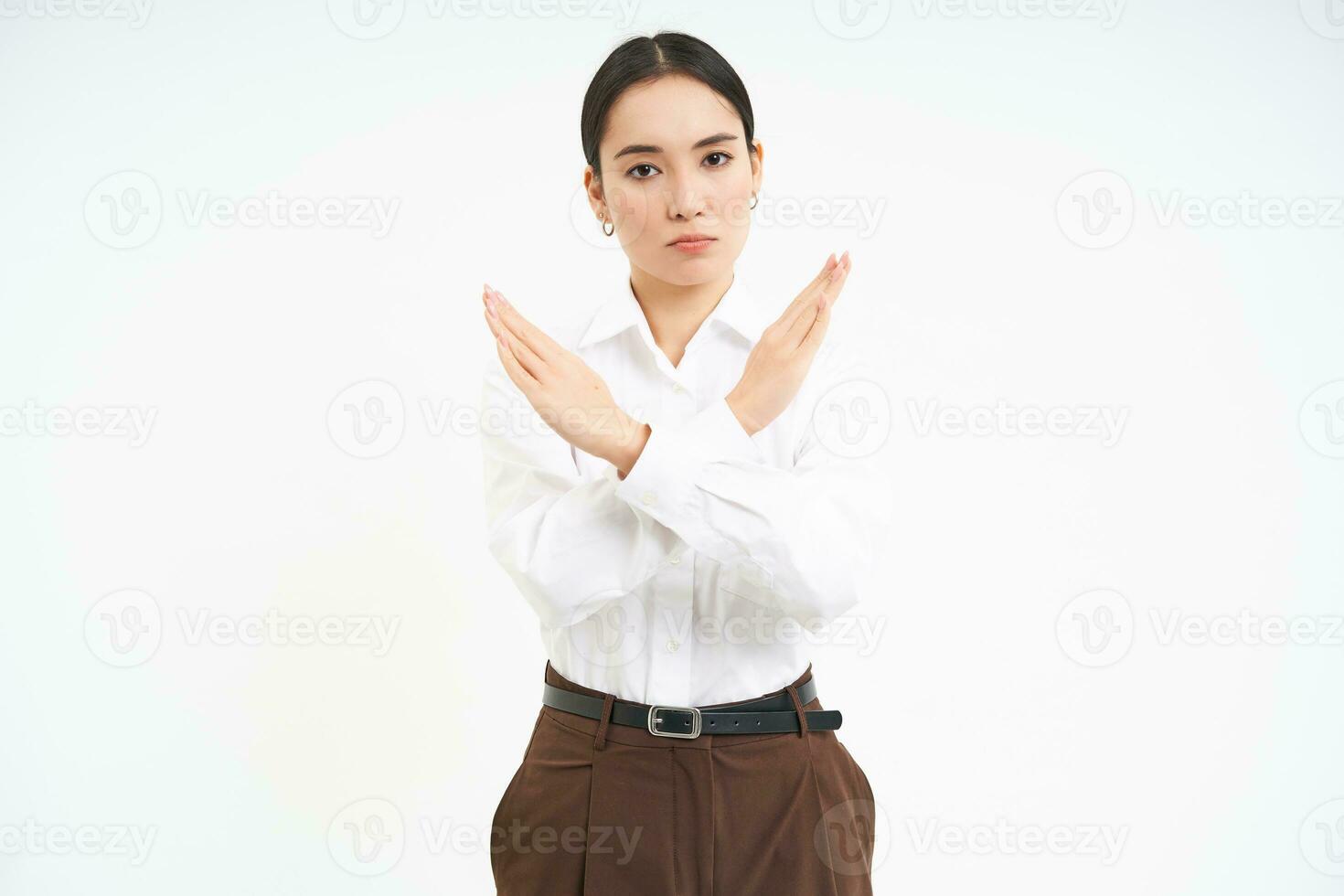 Stop sign. Young serious businesswoman shows cross sign, rejection, prohibit something, standing over white background photo