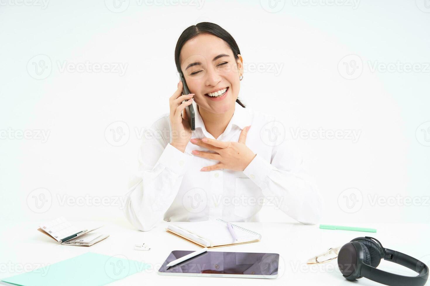 Image of asian woman in office, talks on cellphone, discuss work with client on mobile phone, sits over white background photo