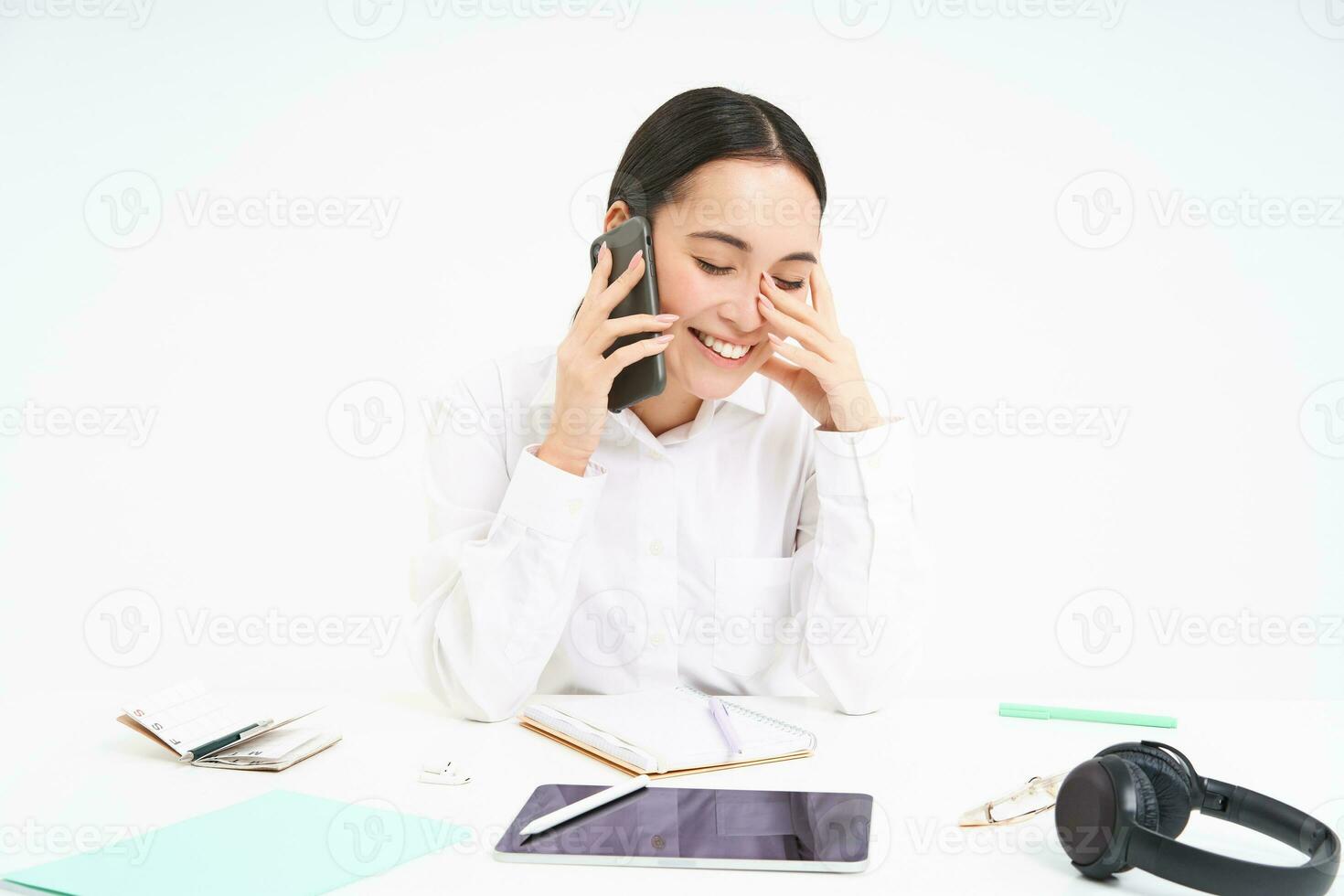 Image of asian woman in office, talks on cellphone, discuss work with client on mobile phone, sits over white background photo
