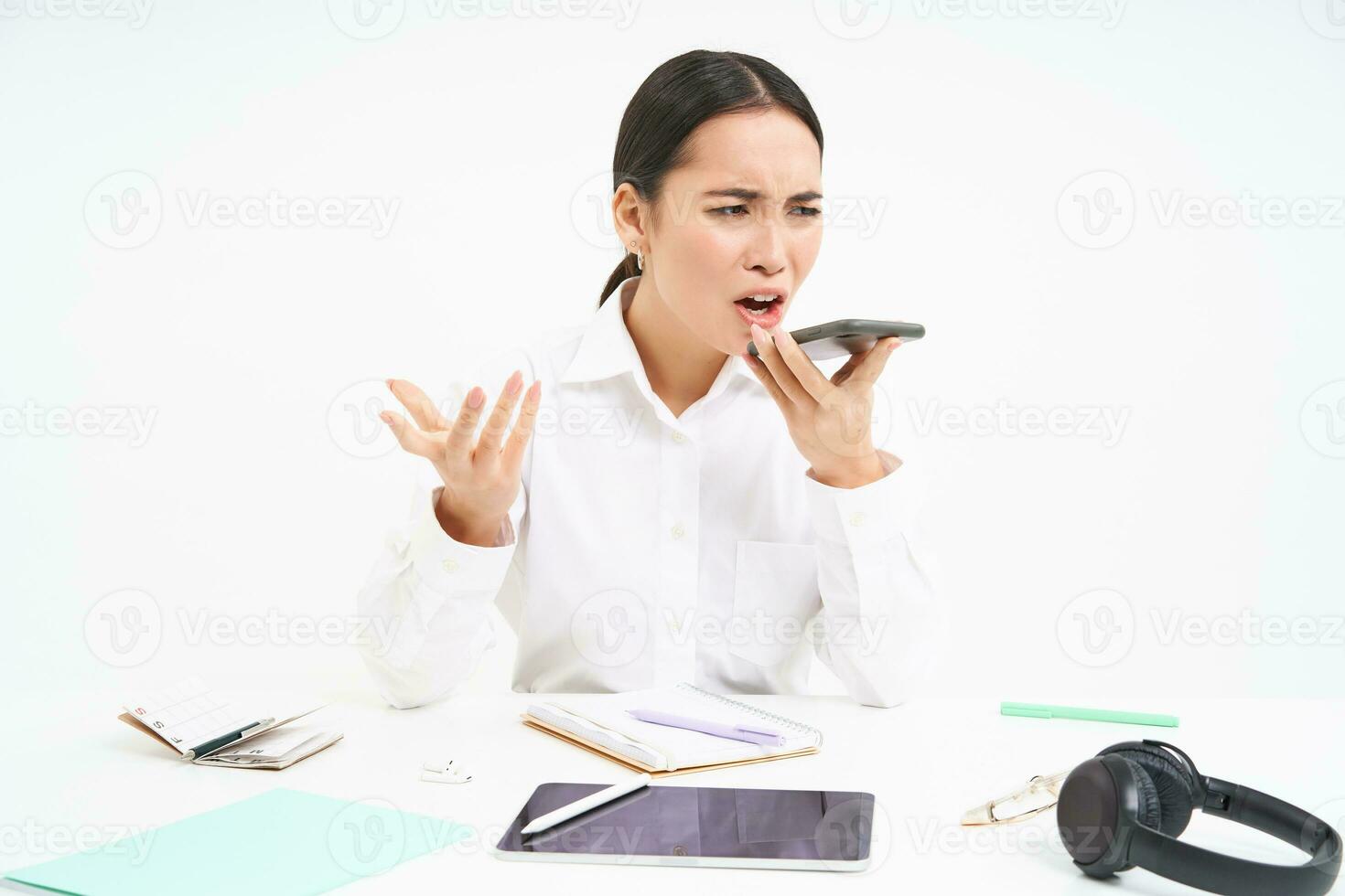 Image of lady boss sits in office, argues on phone, shouts at mobile speakerphone, white background photo
