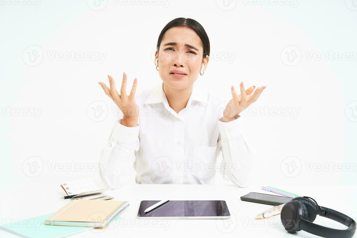 Business and corporate people. Asian office employee sits in workplace, complains, shakes hands with frustrated face, white background photo