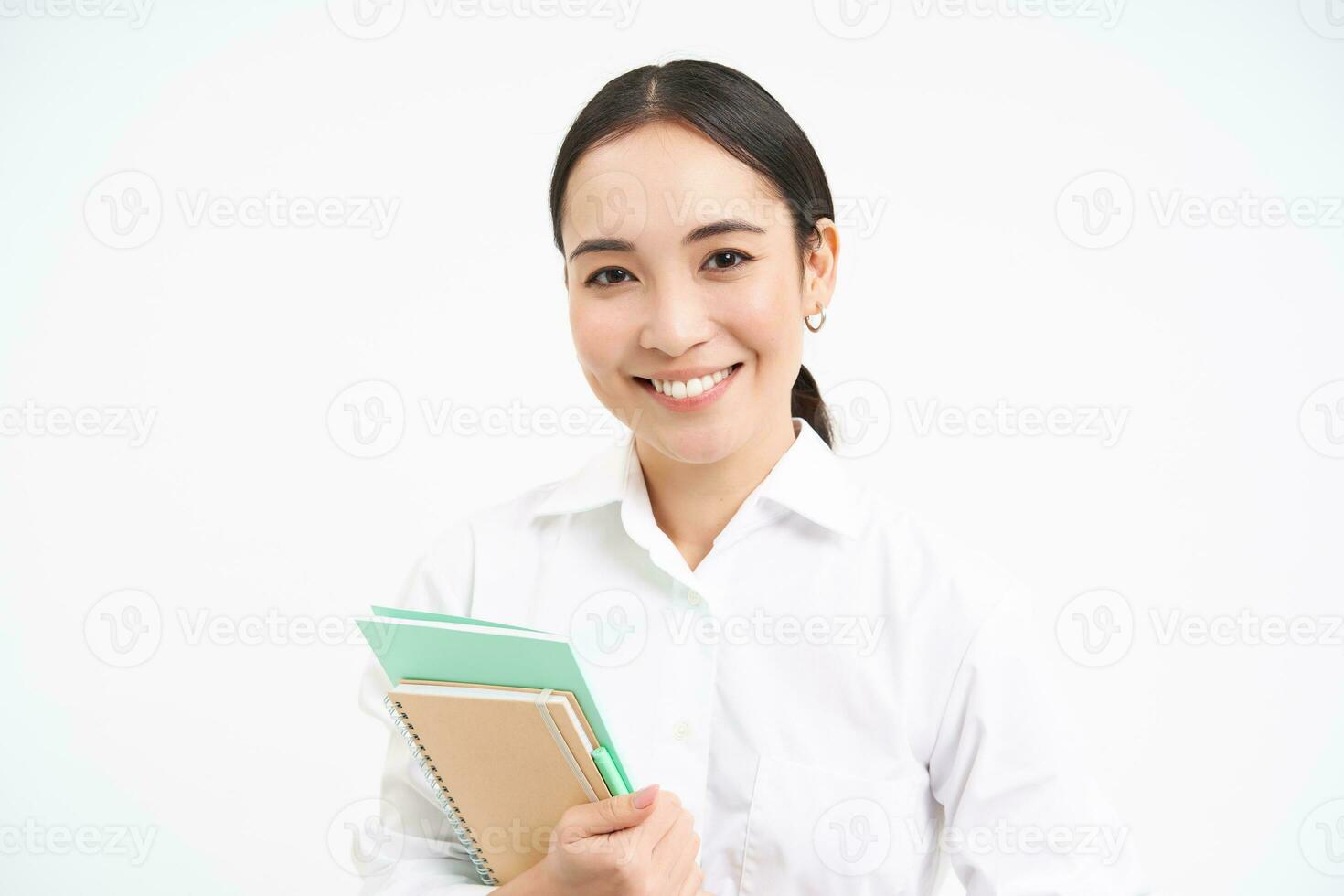 asiático mujer, profesor con cuadernos, sonriente y mirando seguro, aislado en blanco antecedentes foto