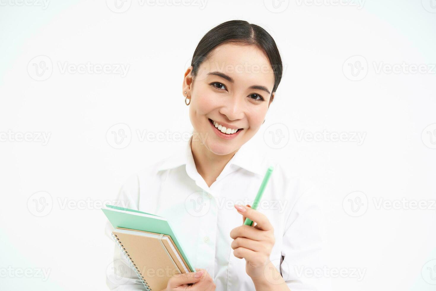hermosa confidente coreano mujer, estudiante con bolígrafo y cuadernos, sonriente y mirando feliz, en pie terminado blanco antecedentes foto