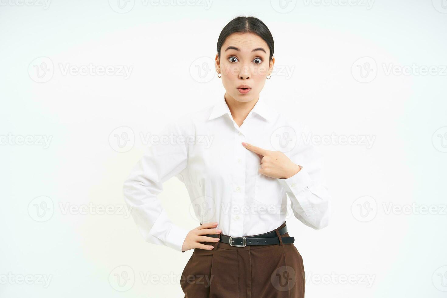 Portrait of asian woman looks surprised, points at herself with amazement, white background photo