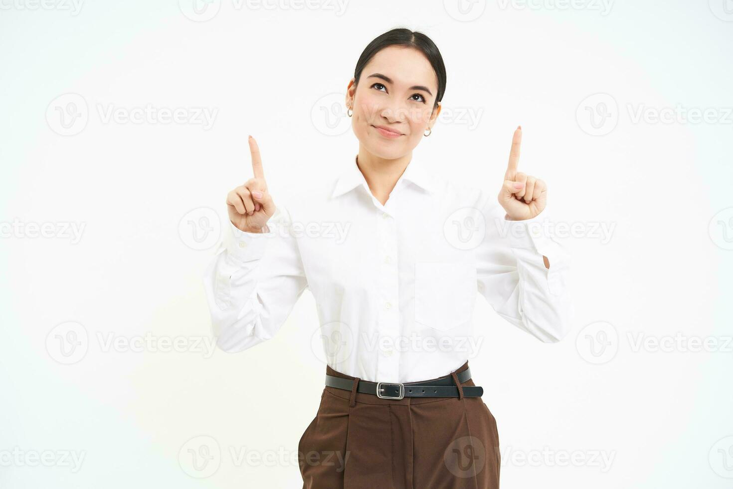 Image of female entrepreneur, points fingers up, shows advertisement on top, smiles with pleased face, white background photo
