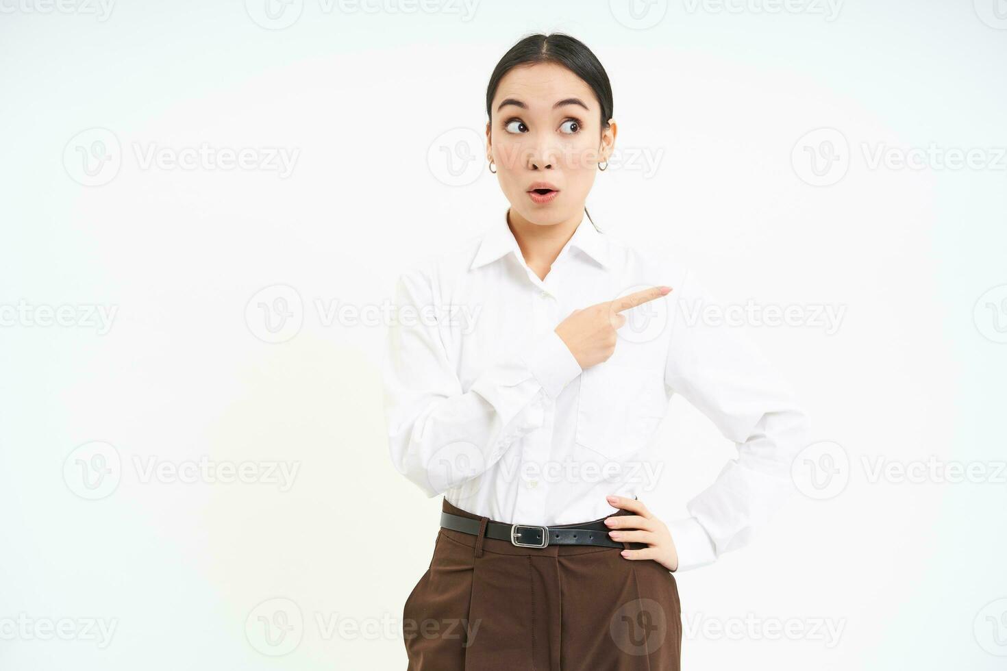 Portrait of korean woman, office lady pointing right, looking with curious face at banner, showing smth interesting, white background photo