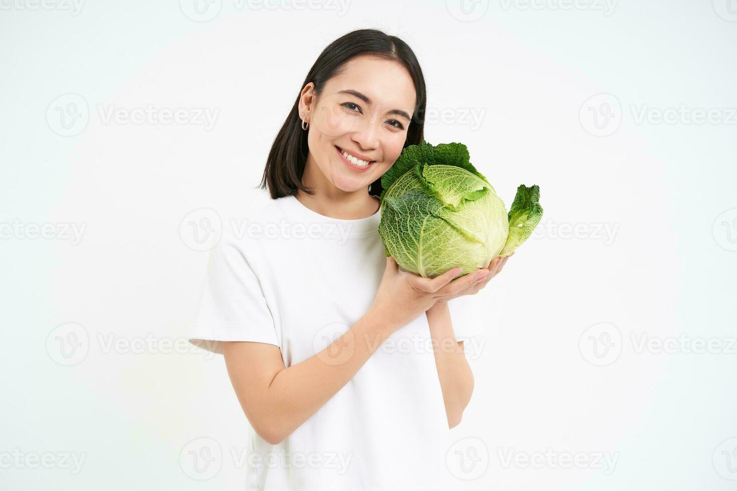 Lovely smiling woman, holding cabbage, posing with lettuce against white background photo